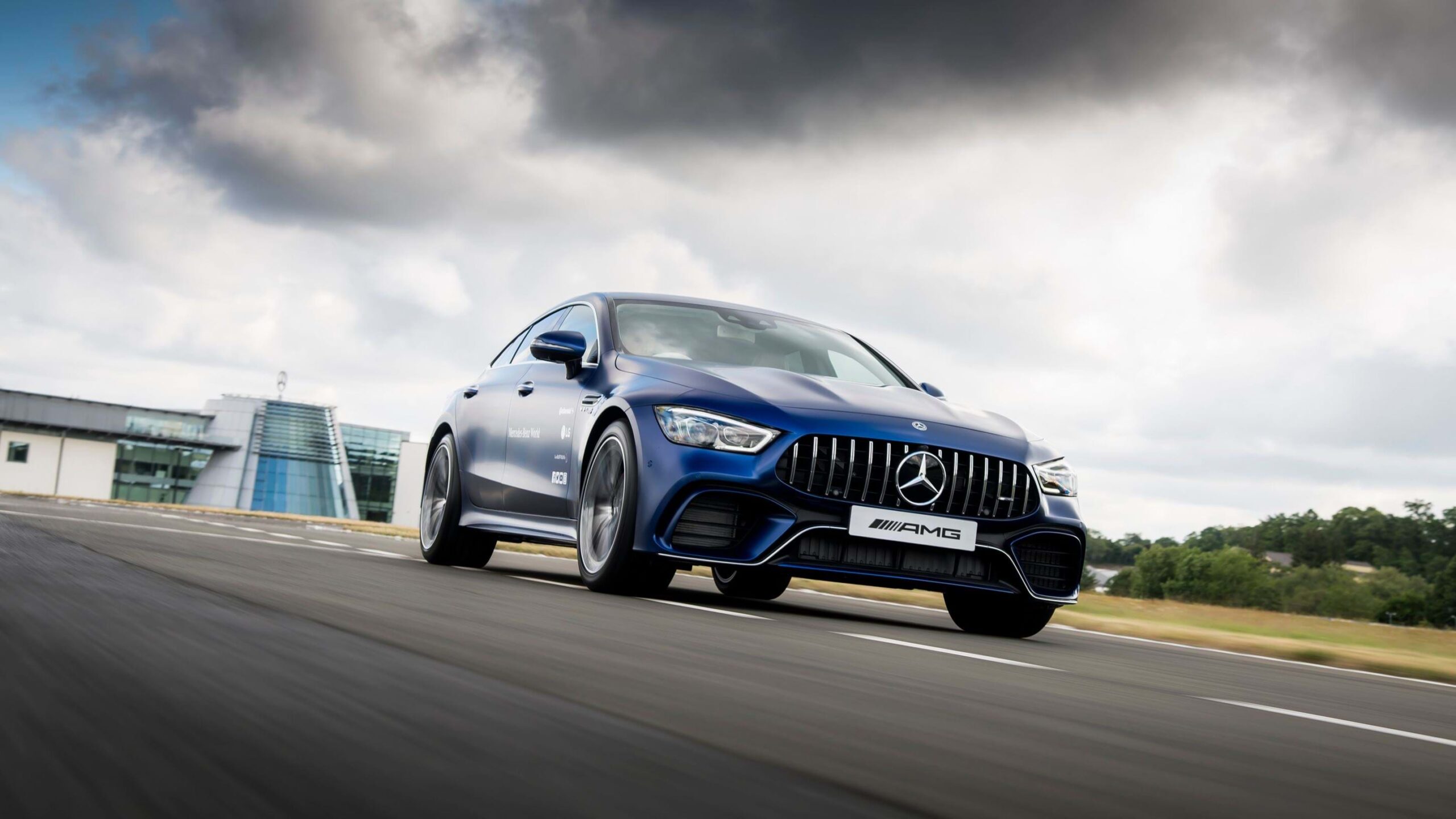 A Mercedes Benz car driving on a tarred road under a cloudy sky