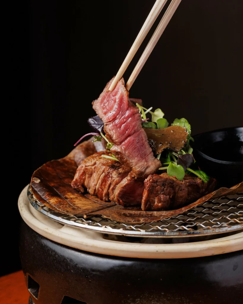 a piece of meat with chopsticks on a plate